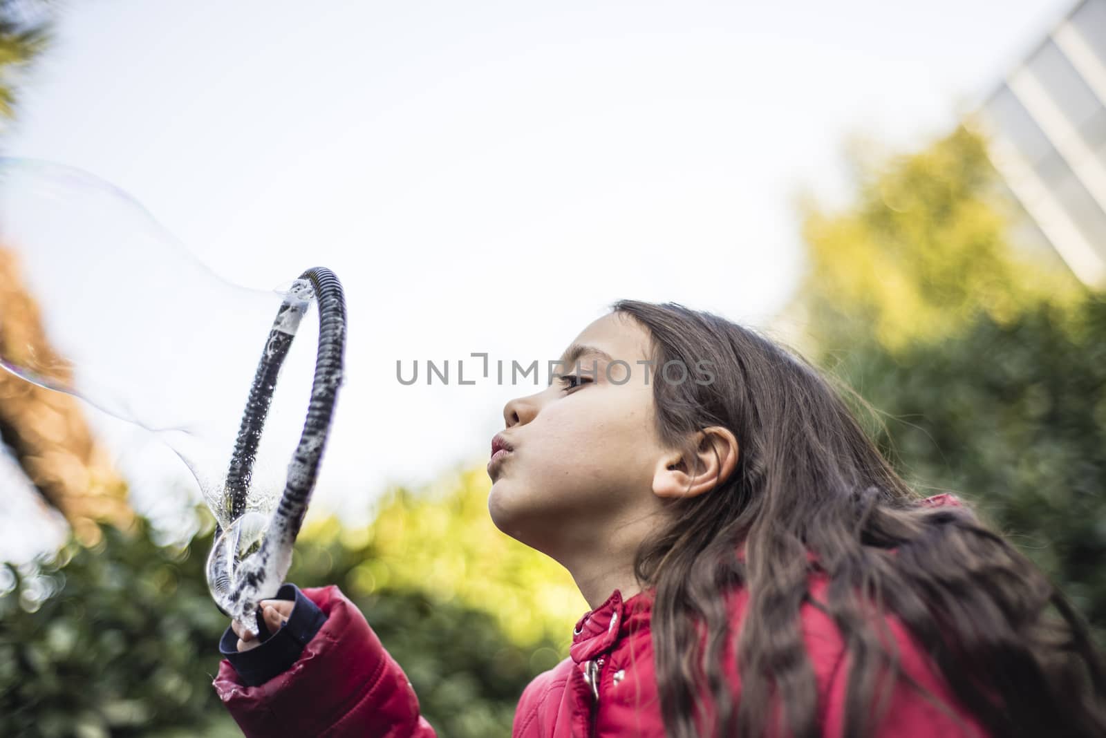 7 year old girl in outdoor in the garden in winter makes big soap bubbles