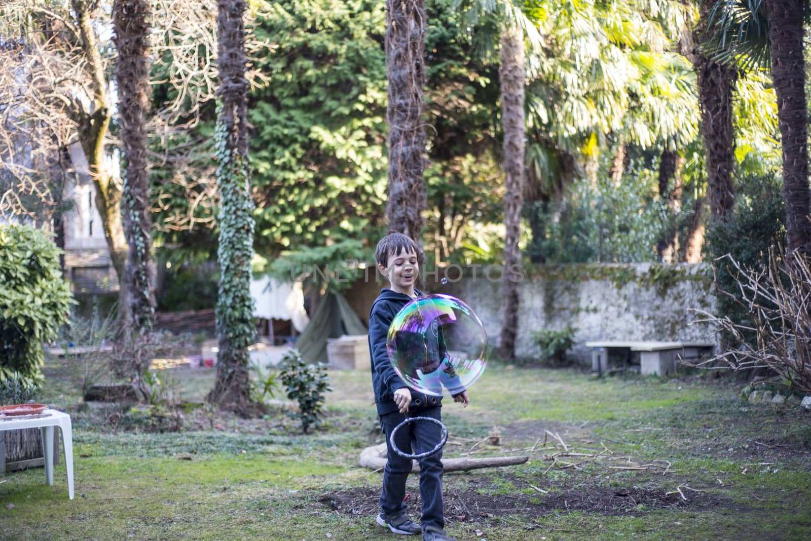 7-year-old child outdoors in the garden in winter makes big soap bubbles