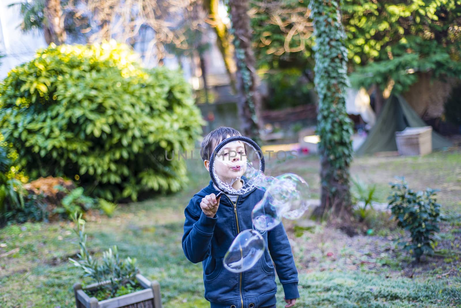 7-year-old child outdoors in the garden in winter makes big soap bubbles