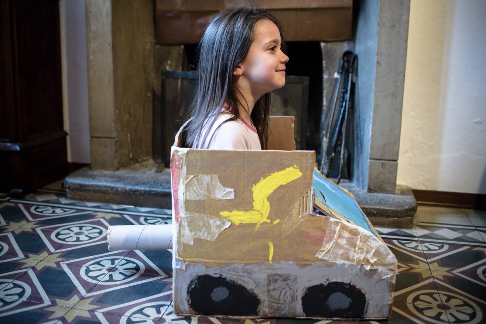 5-year-old girl plays with a self-made cardboard car, at home in her pajamas in the morning