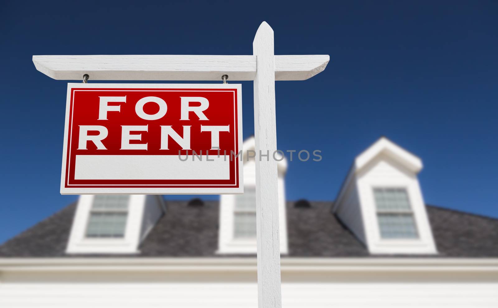 Left Facing For Rent Real Estate Sign In Front of House and Deep Blue Sky.