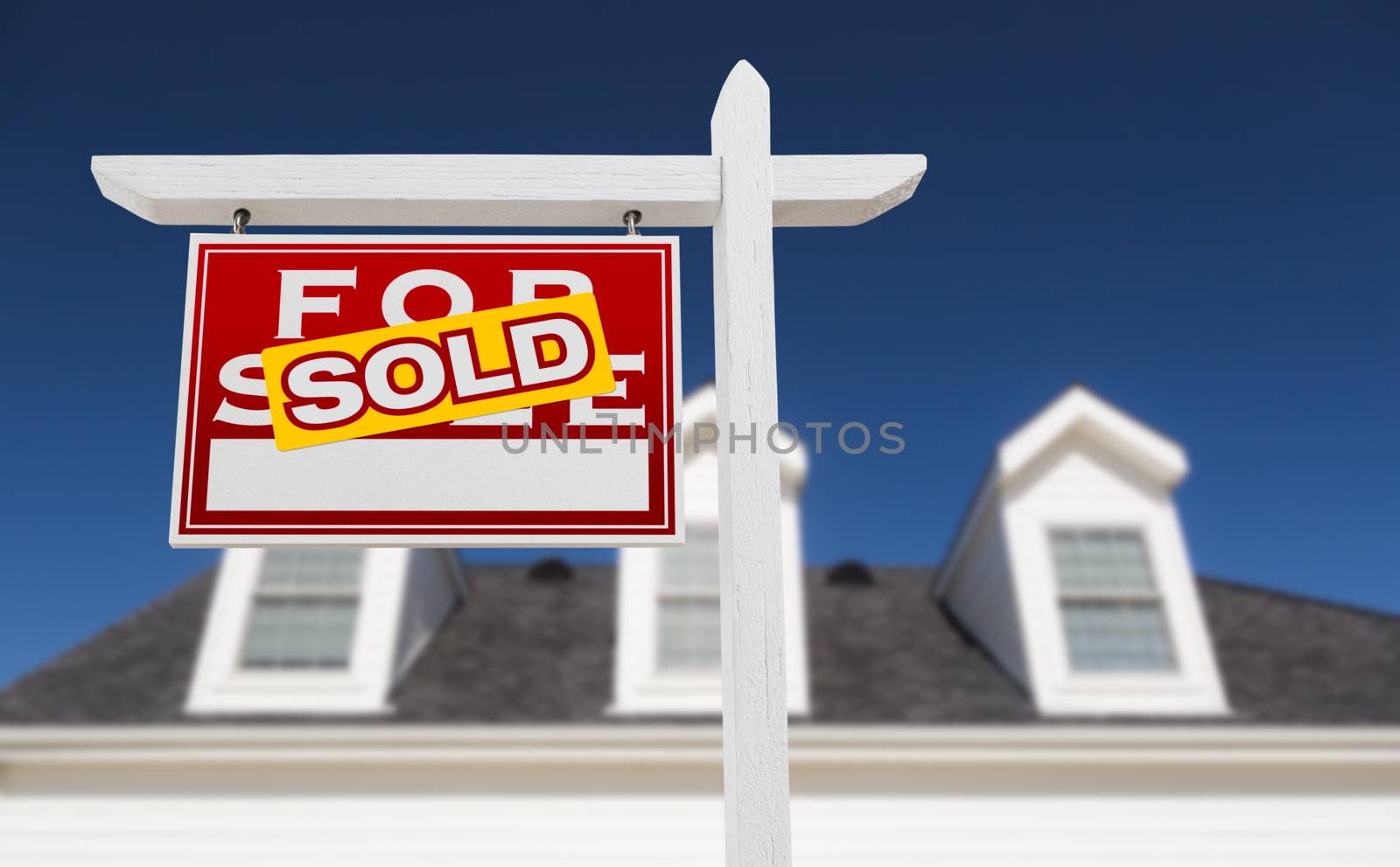 Left Facing Sold For Sale Real Estate Sign In Front of House and Deep Blue Sky.