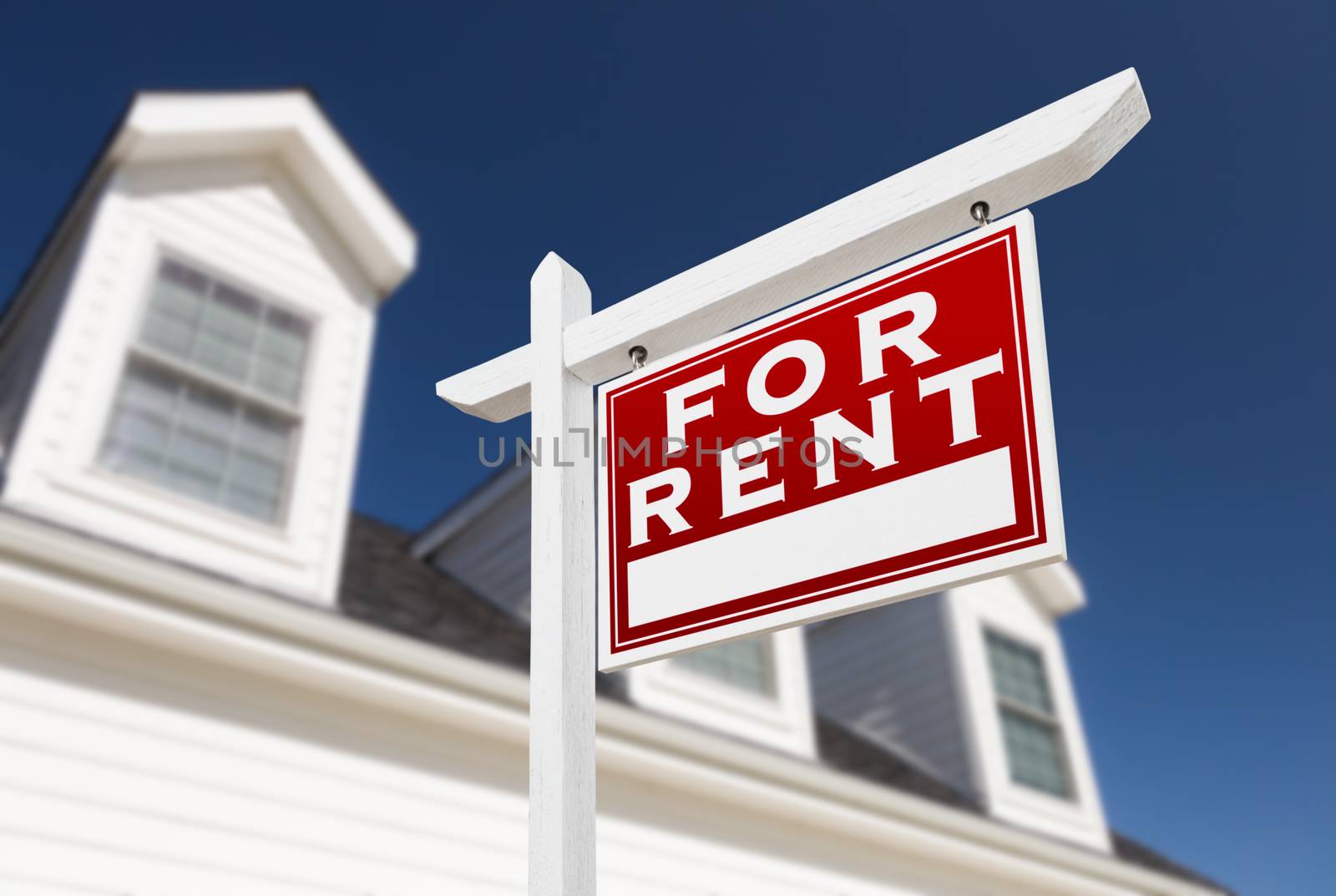 Right Facing For Rent Real Estate Sign In Front of House and Deep Blue Sky.