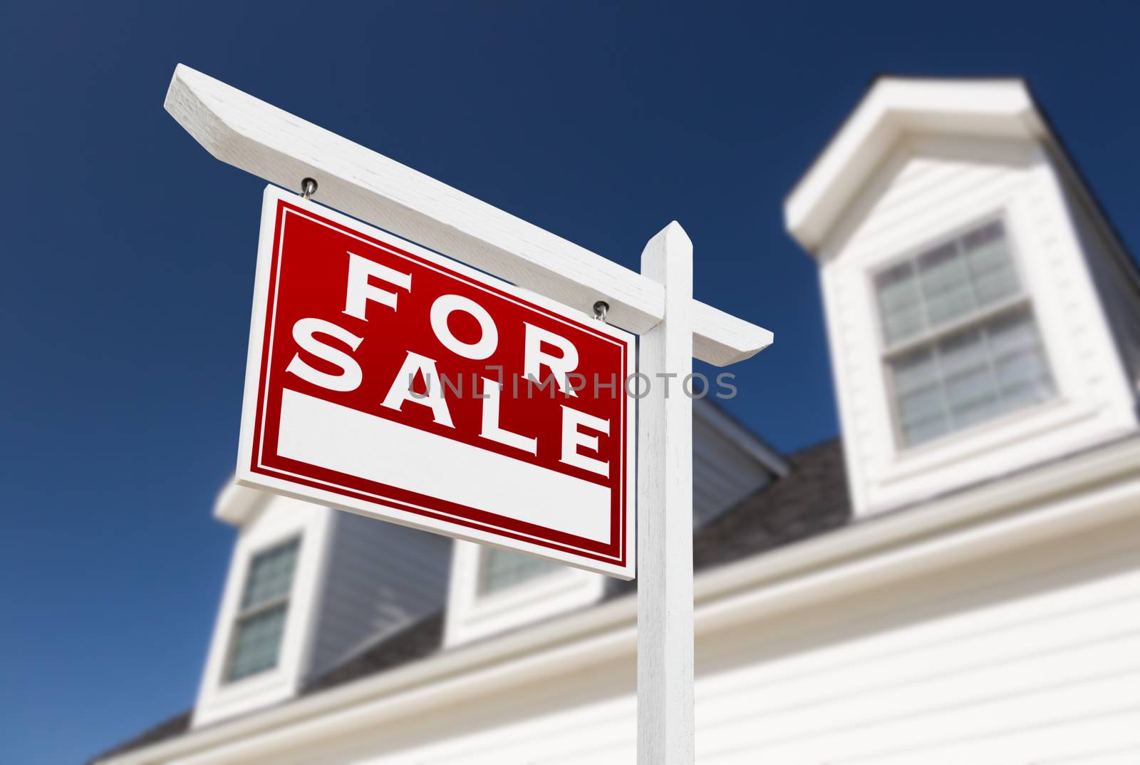 Left Facing For Sale Real Estate Sign In Front of House and Deep Blue Sky.