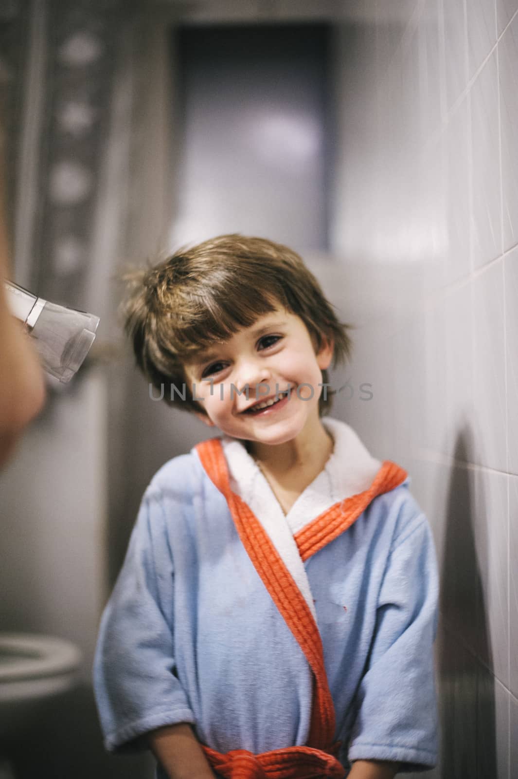 mother dries her son's hair with the hair dryer after the bath