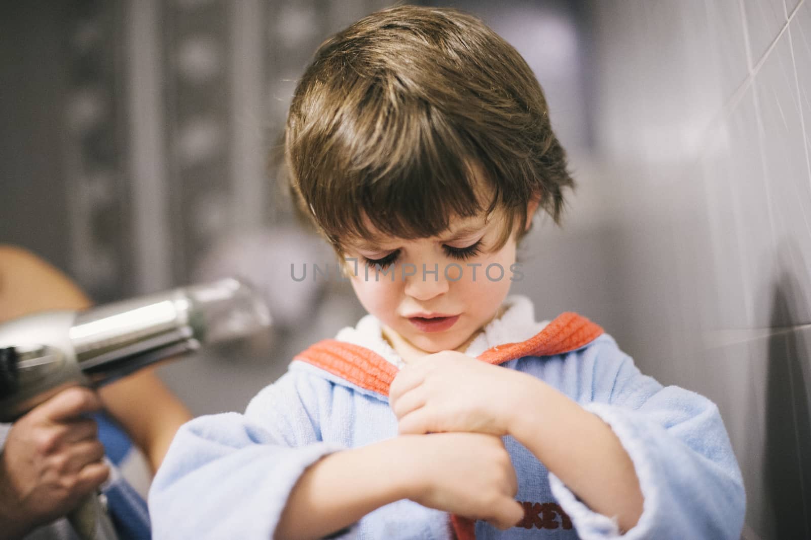 mother dries her son's hair with the hair dryer after the bath