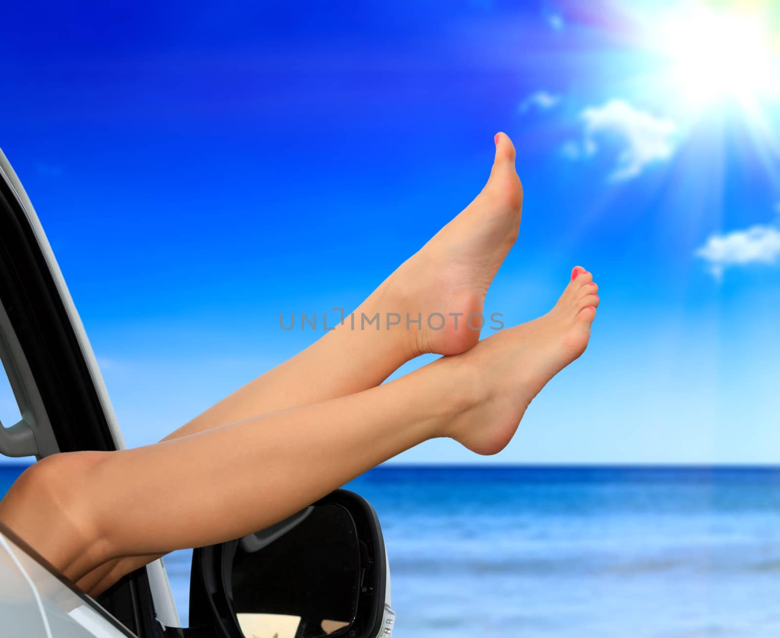 Beaitiful female legs against the sea and summer blue sky. Vacation, travel summer holidays concept. Woman shows her slim legs from the car window