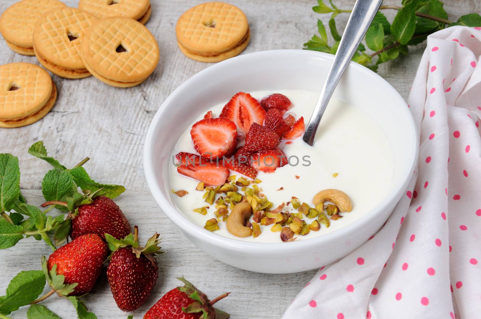 Chilled Buttermilk soup from Greek yogurt with strawberries and pistachios, cashews. Serve with crispy biscuits. Vertical shot.