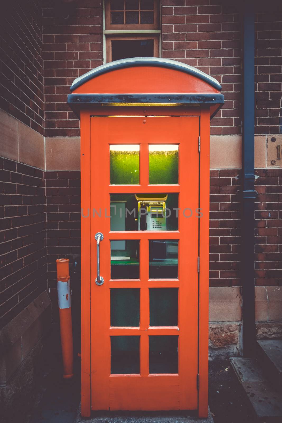 Vintage UK red phone booth in front of a brick wall