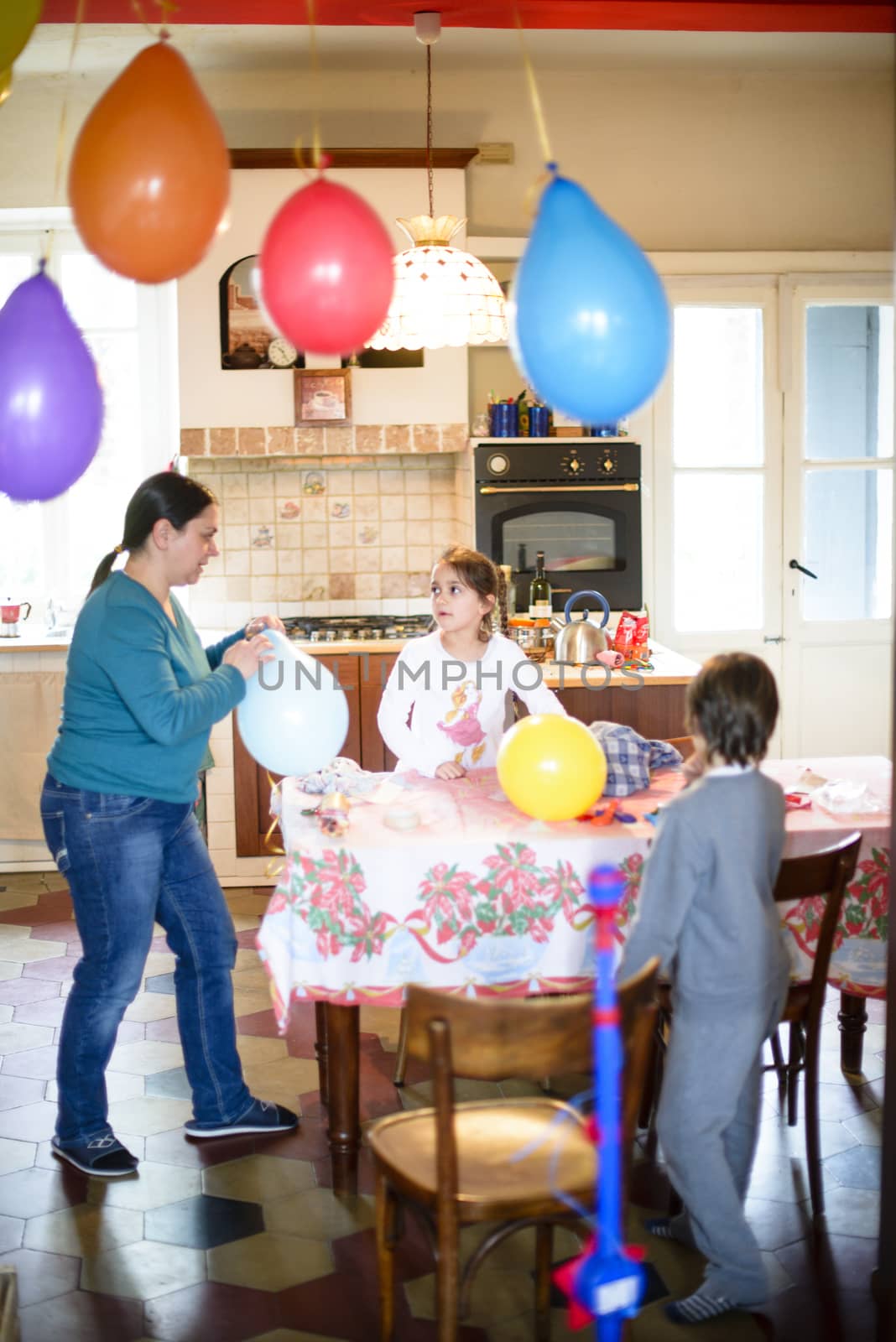 mother and children prepare kitchen hanging colorful balloons for birthday party