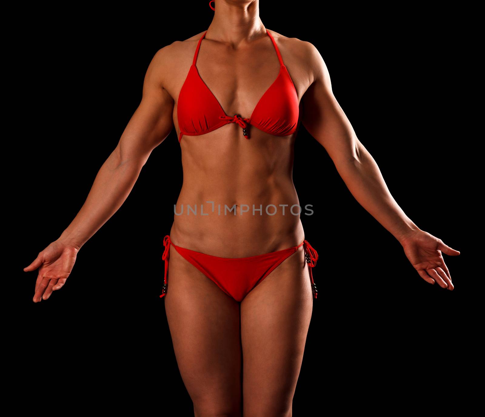 Sexy sports woman in red bikini posing against black background