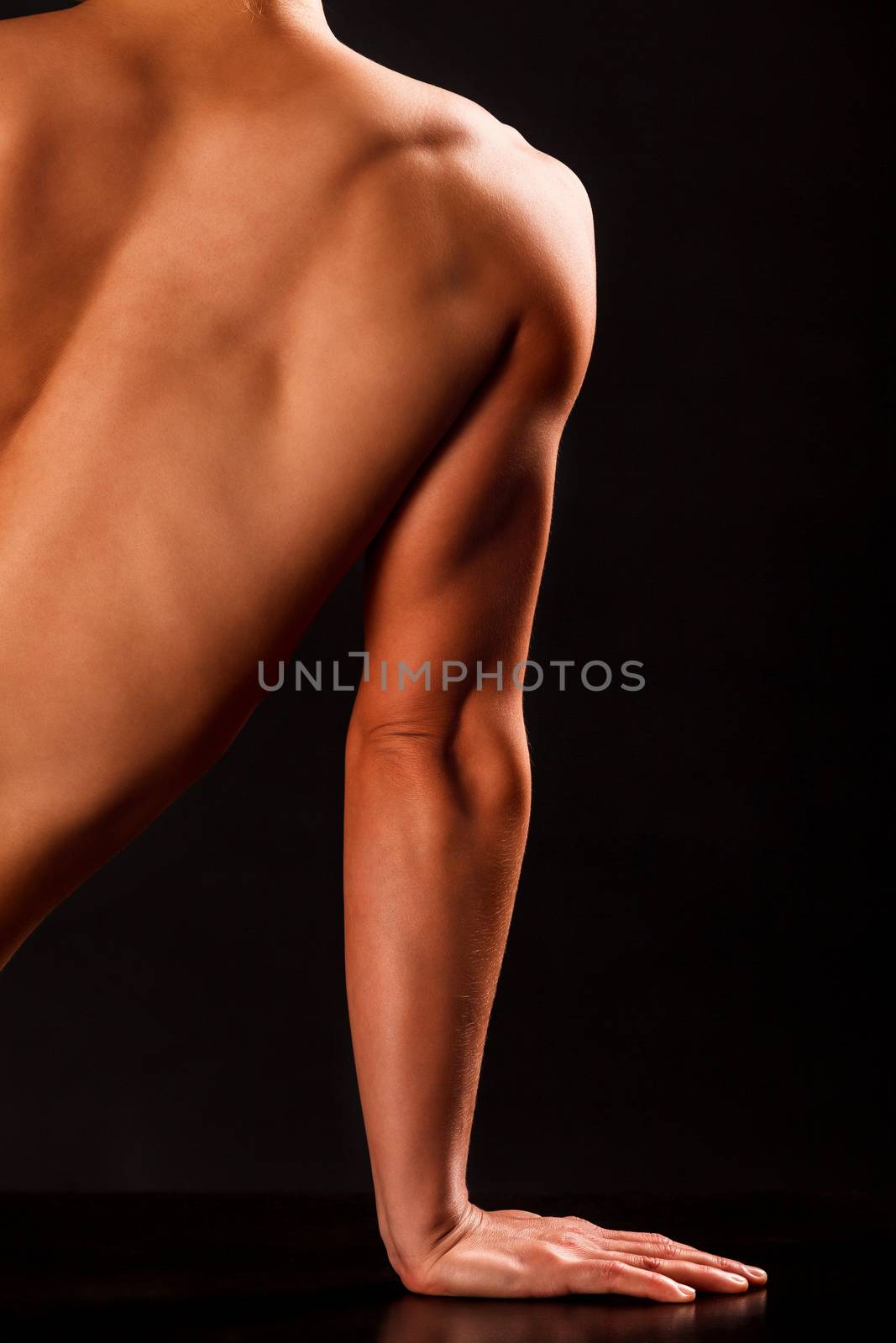 Arm and part of back of muscular woman posing against black background