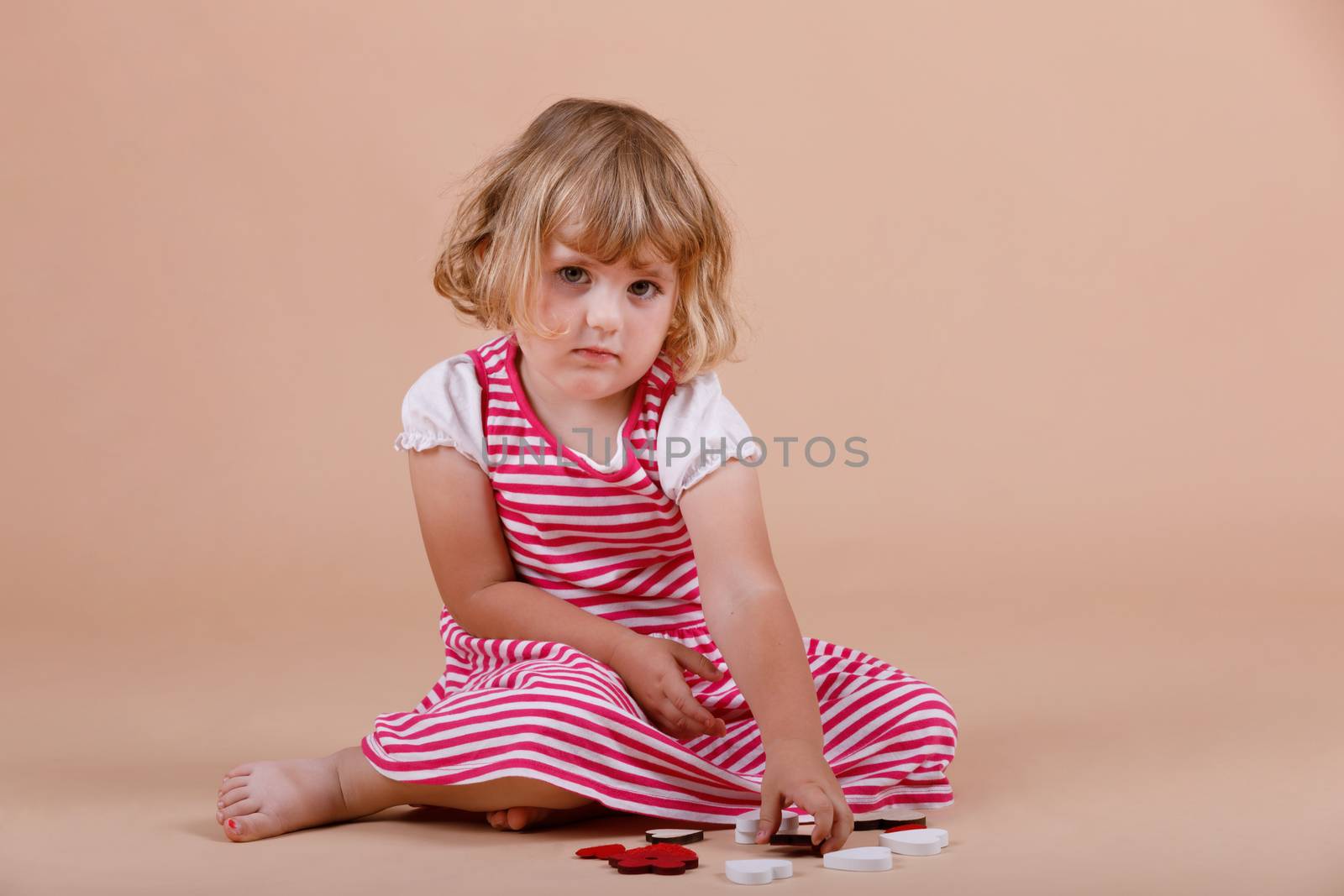 studio portrait of young cute baby girl, three years old on beige background