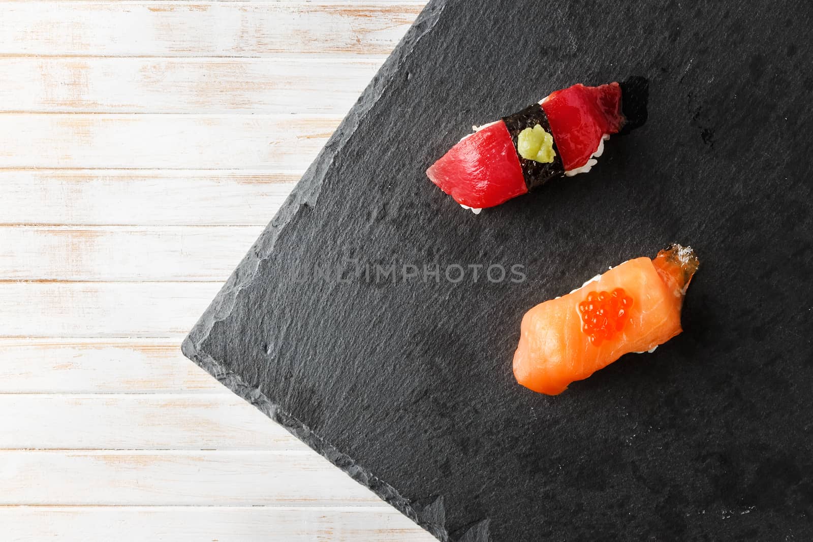 Salmon Nigiri with Salmon Roe and red tuna with wasabi paste Nigiri on black slate stone seen from above. Raw fish in traditional Japanese sushi style. Horizontal image.