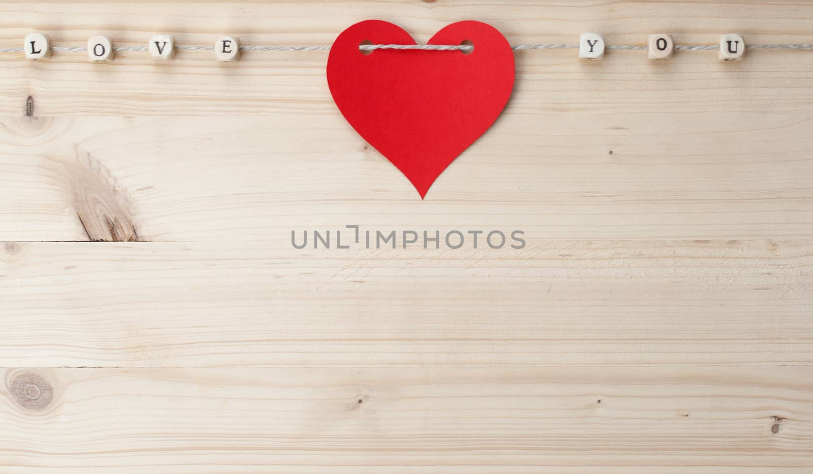 The words Love You and a heart on a cord on wood