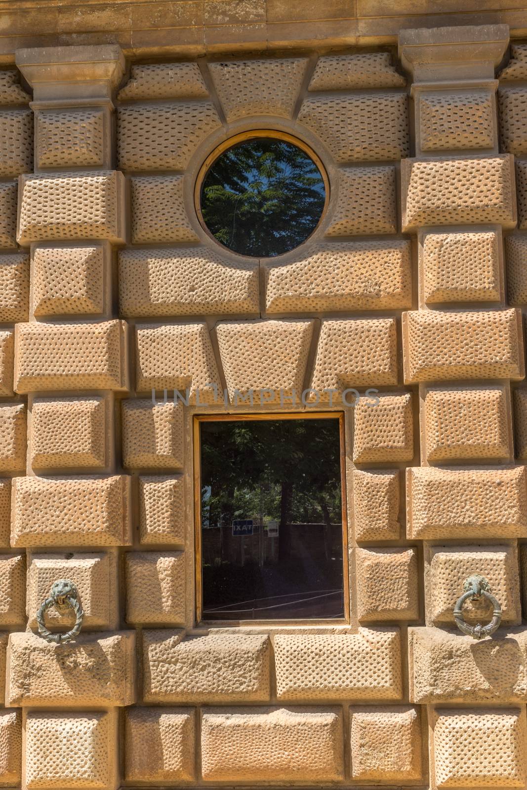 Bronze ring with a lion head figure on the exterior wall of Charles V Palace at Alhambra Palace complex in Granada, Andalusia, Spain, Europe on a bright summer day