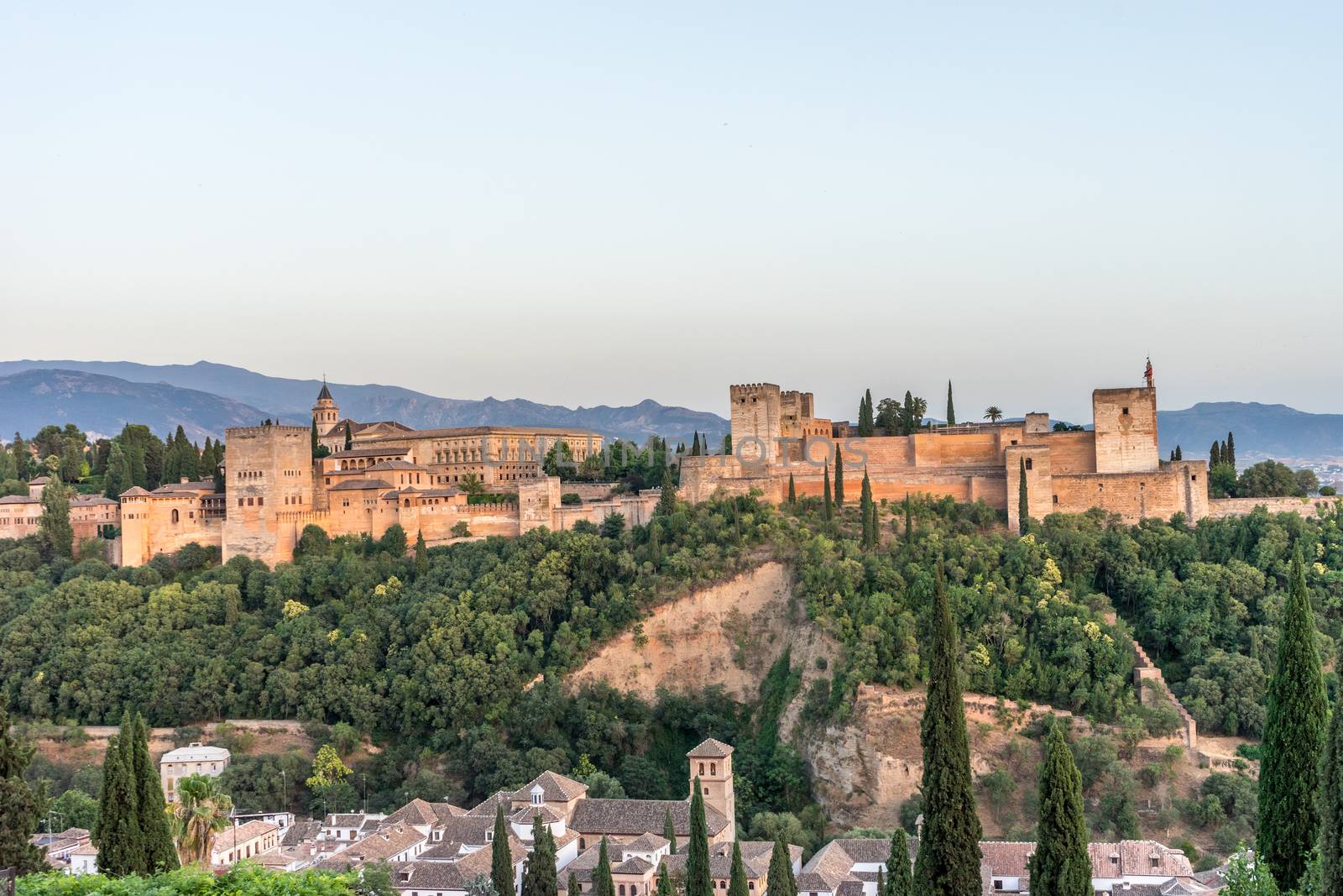 The magnificient Alhambra of Granada, Spain. Alhambra fortress at sunset viewed from Mirador de San Nicolas during evening twilight hour.