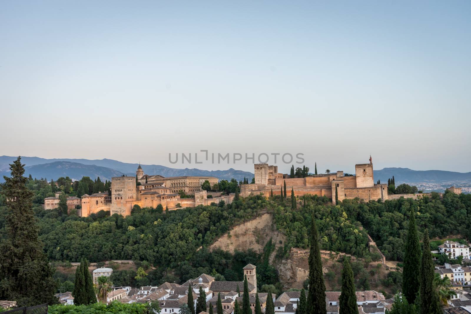 The magnificient Alhambra of Granada, Spain. Alhambra fortress at sunset viewed from Mirador de San Nicolas during evening twilight hour.