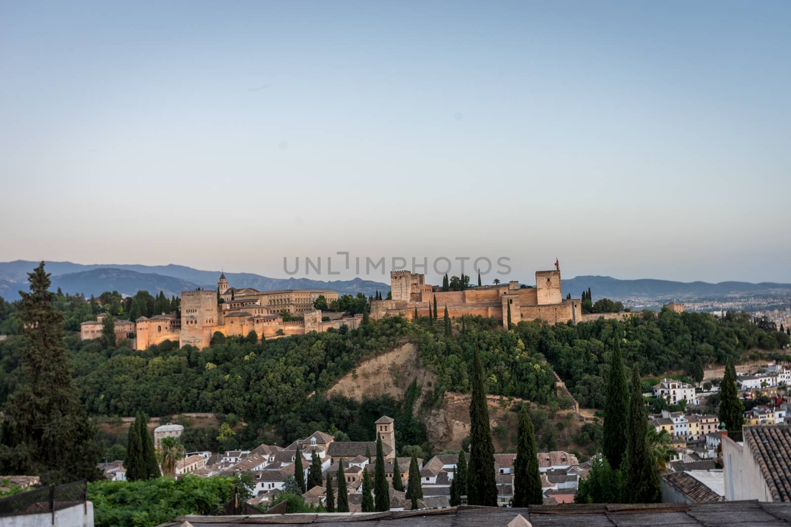 The magnificient Alhambra of Granada, Spain. Alhambra fortress at sunset viewed from Mirador de San Nicolas during evening twilight hour.