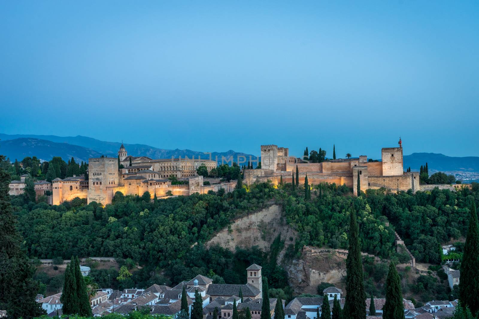 The magnificient Alhambra of Granada, Spain. Alhambra fortress at sunset viewed from Mirador de San Nicolas during evening twilight hour.