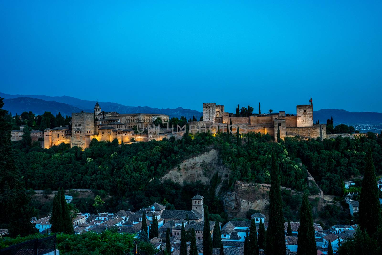 The magnificient Alhambra of Granada, Spain. Alhambra fortress at sunset viewed from Mirador de San Nicolas during evening twilight hour.