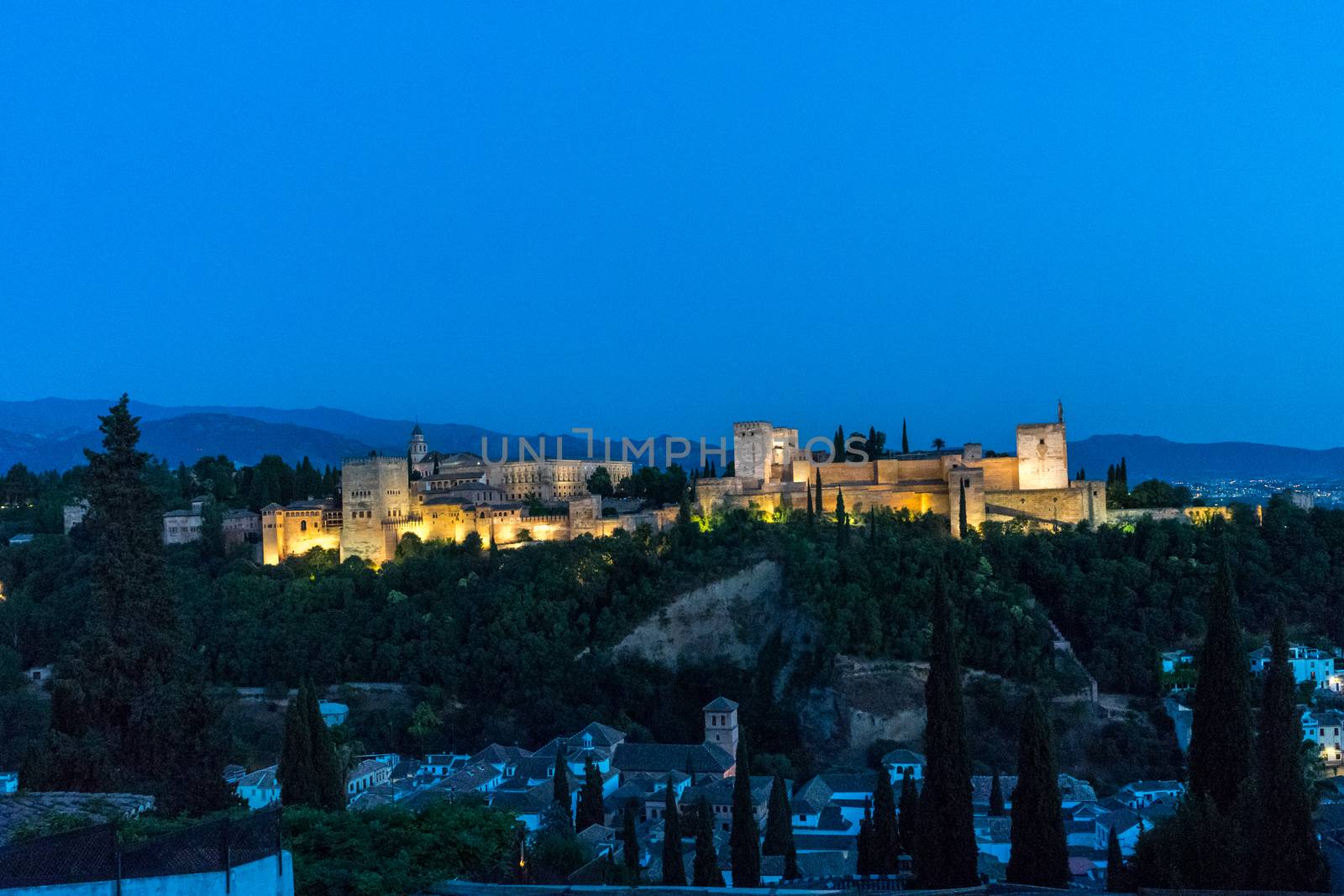 The magnificient Alhambra of Granada, Spain. Alhambra fortress at sunset viewed from Mirador de San Nicolas during evening twilight hour.