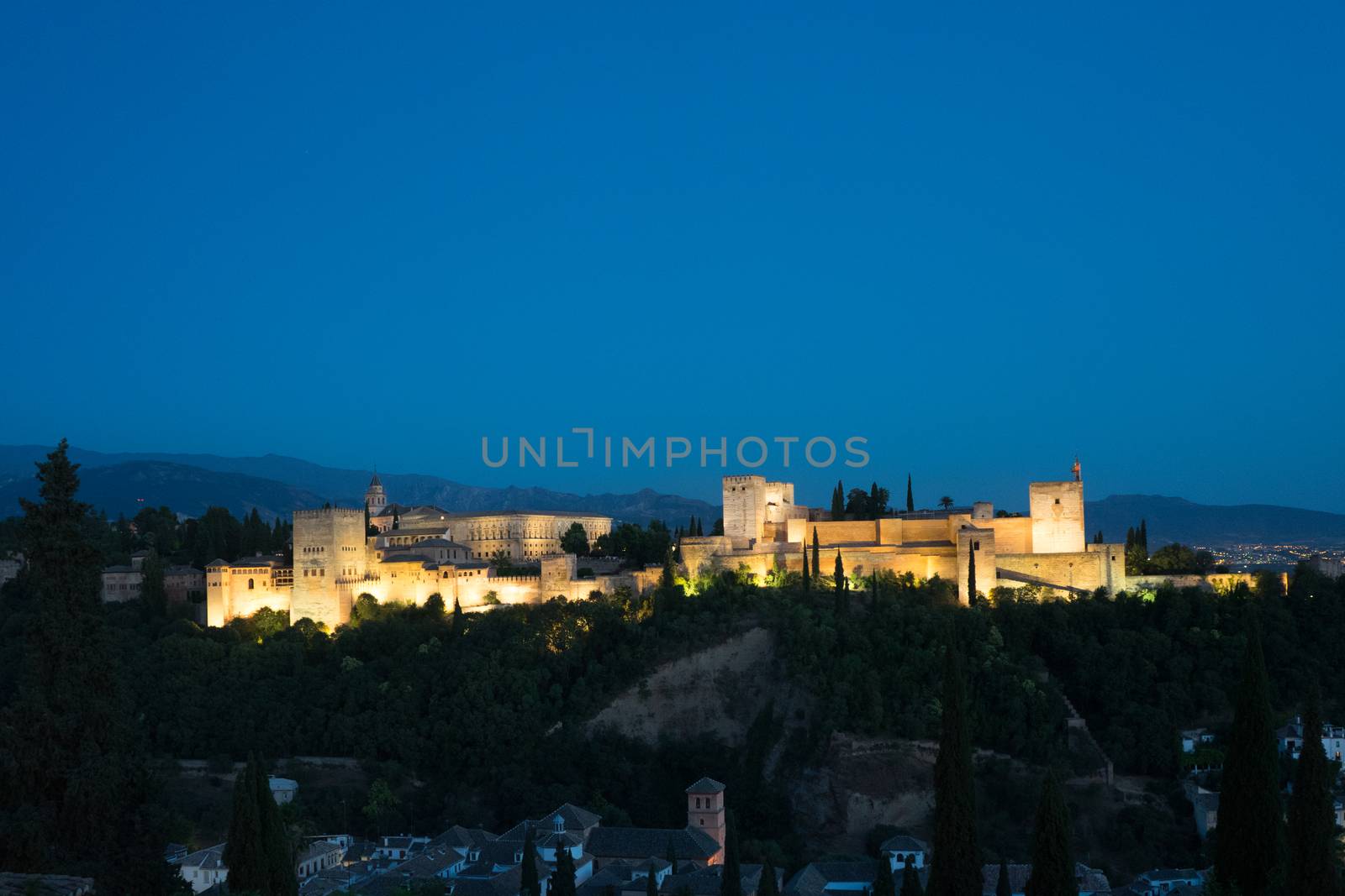 The magnificient Alhambra of Granada, Spain. Alhambra fortress at sunset viewed from Mirador de San Nicolas during evening twilight hour.