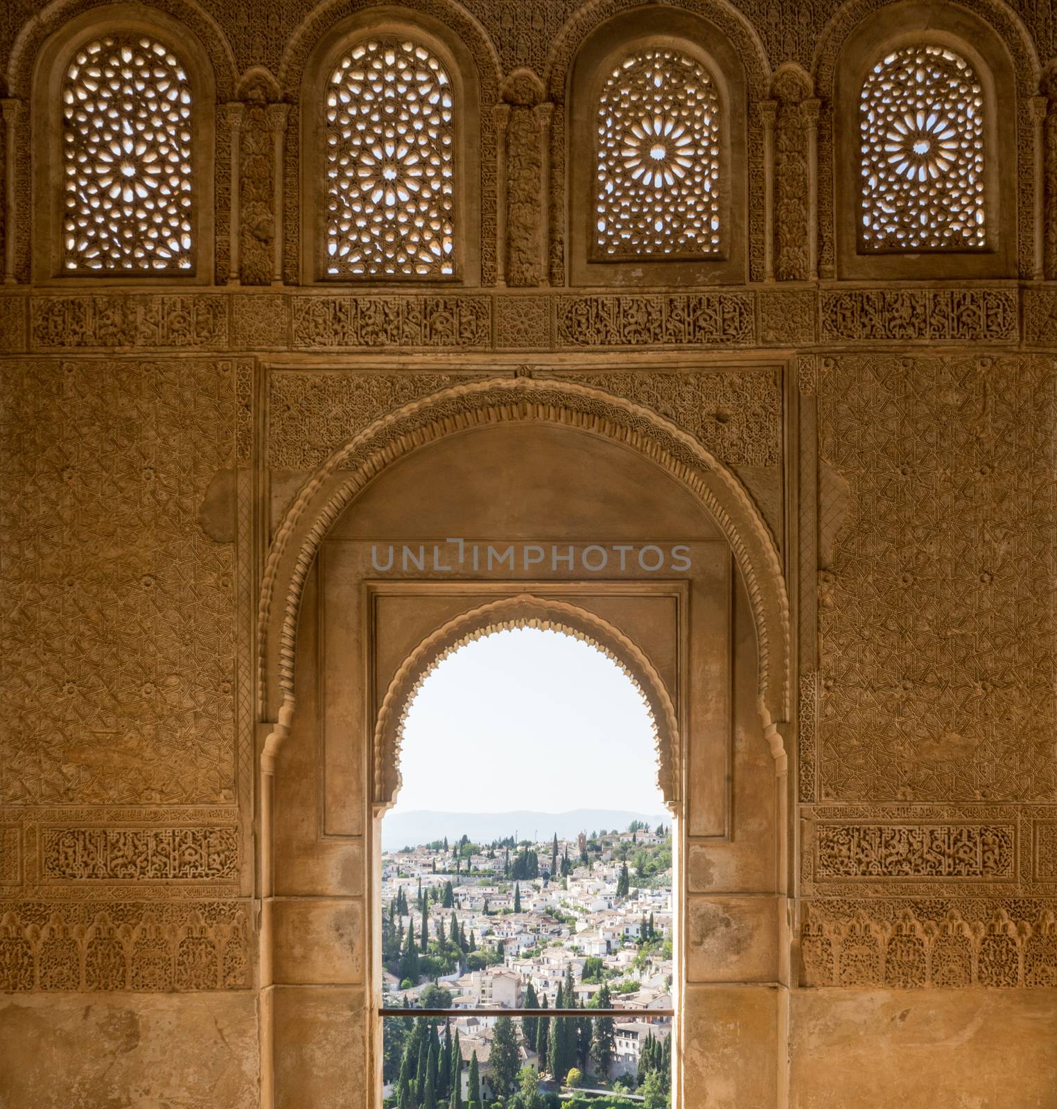 View of the Albayzin district of Granada, Spain, from an arched window in the Alhambra palace near sunset at Granada, Spain, Europe on a bright sunny day