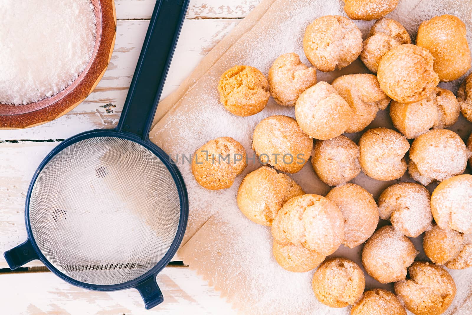 Closeup of castagnole, typical Italian carnival sweet with powdered sugar and sieve seen from above