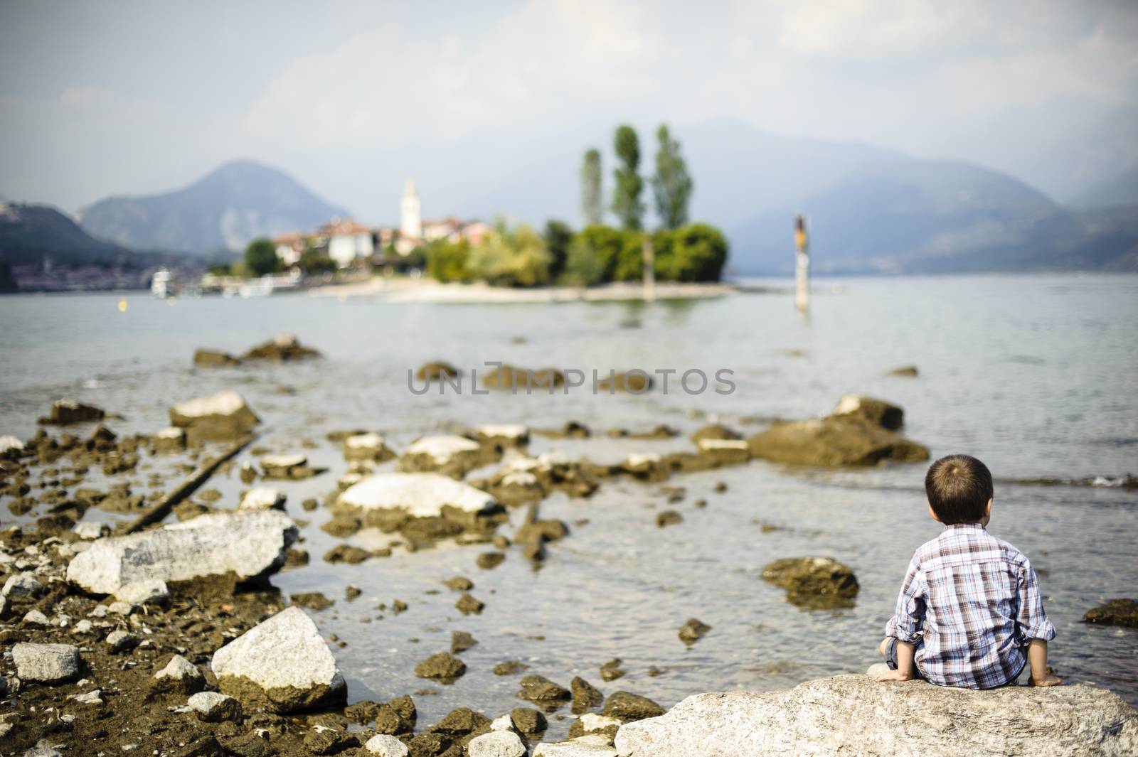 Italy, Piedmont, Isola Bella, Lago Maggiore, a child sitting on a rock looking towards infinite horizon