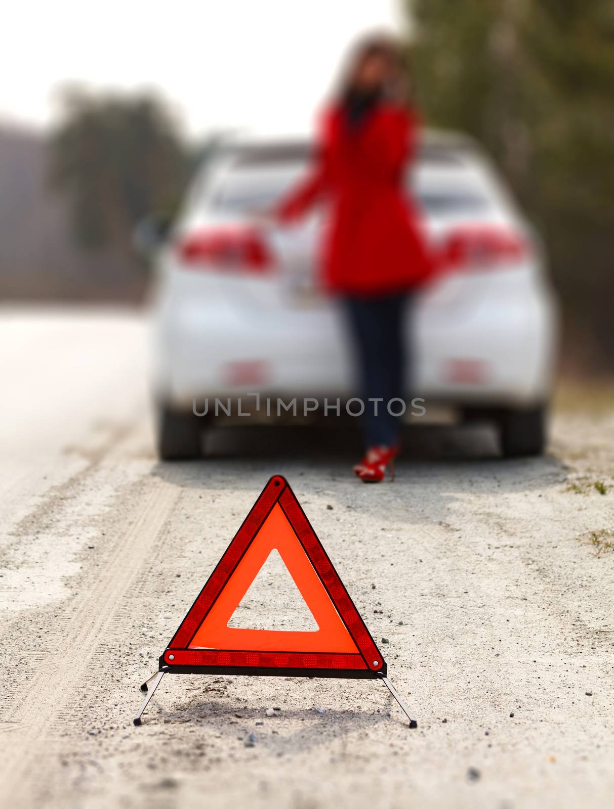 Woman standing by the broken car and warning triangle sign