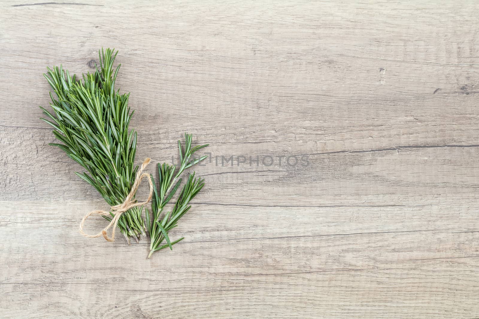 Rosemary bunch of bouquets on light wooden surface. Top view, copy space.