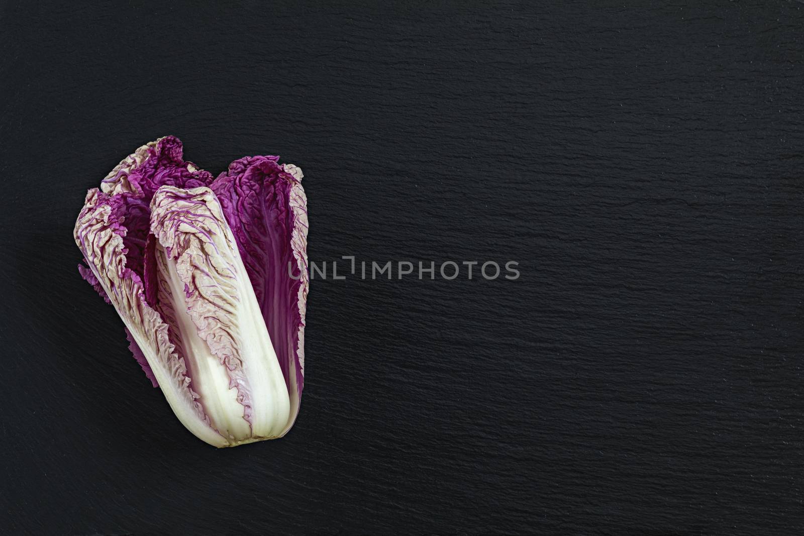 Blue napa cabbage on black stone surface. Top view, copy space.