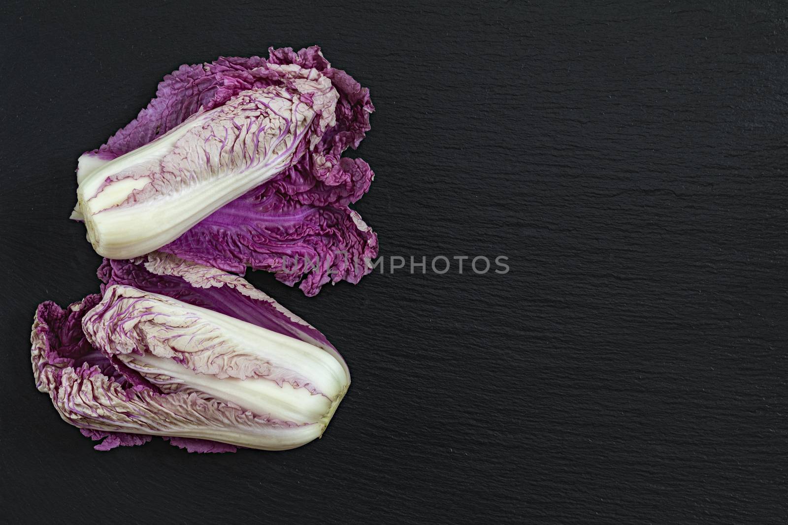 Two blue napa cabbages on black stone surface. Top view, copy space.