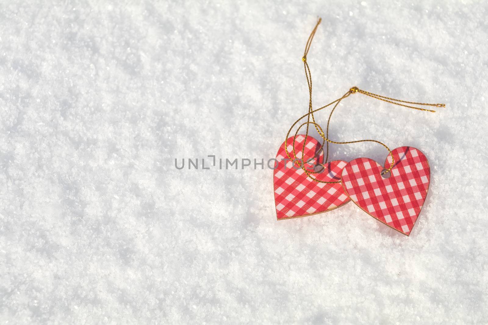Beautiful valentine holiday background with two checkered motley hearts on white snow surface.