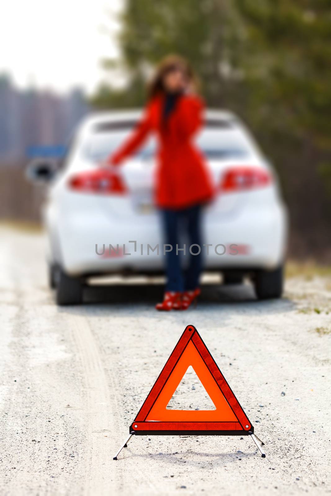 Woman standing by the broken car and warning triangle sign by Nobilior