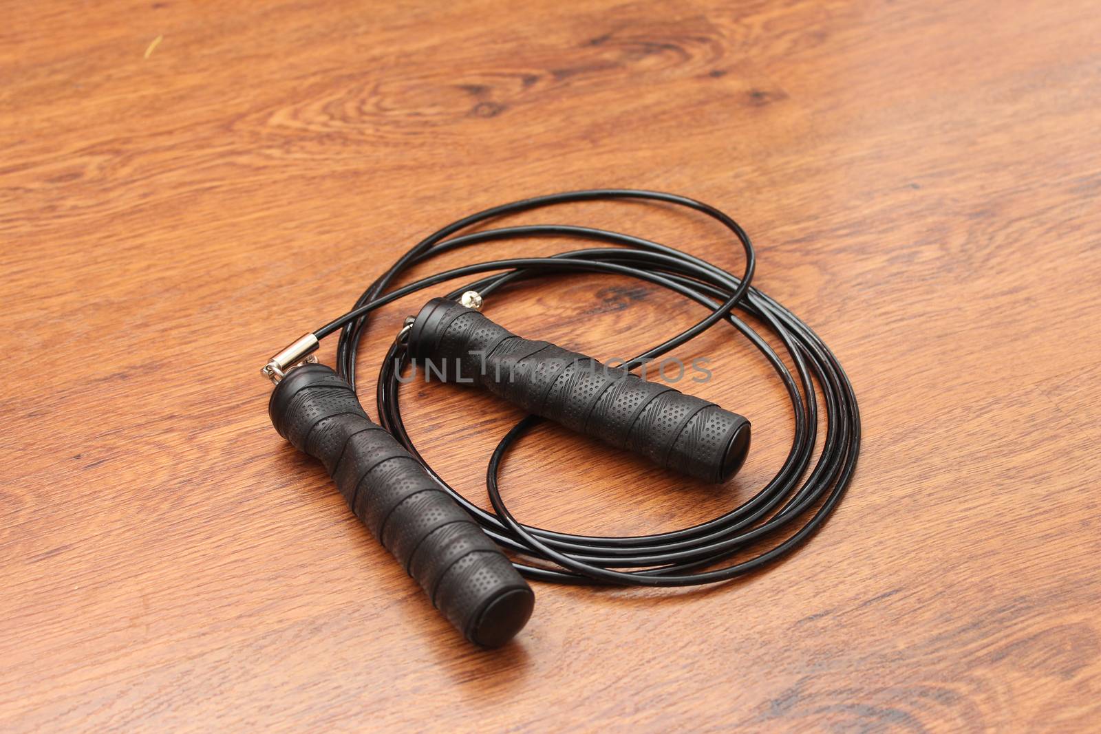 Sports rope on a wooden floor. Speed skipping rope for boxing or fitness.