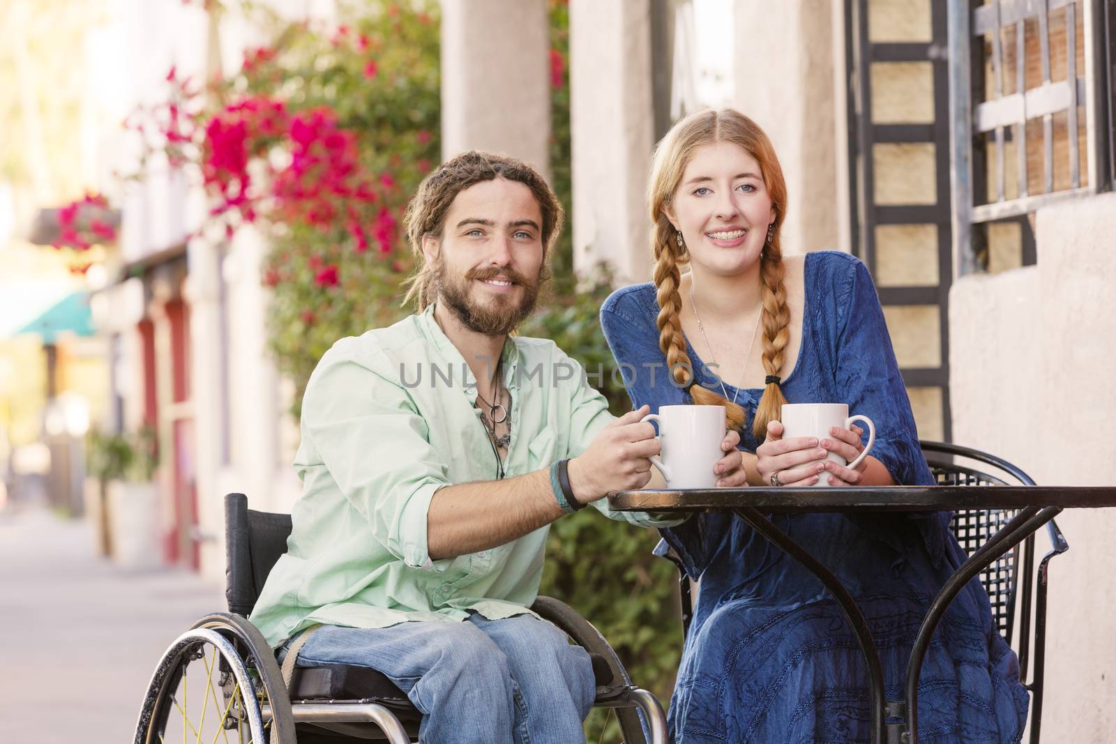 Woman having coffee with male friend in wheelchair at outdoor cafe