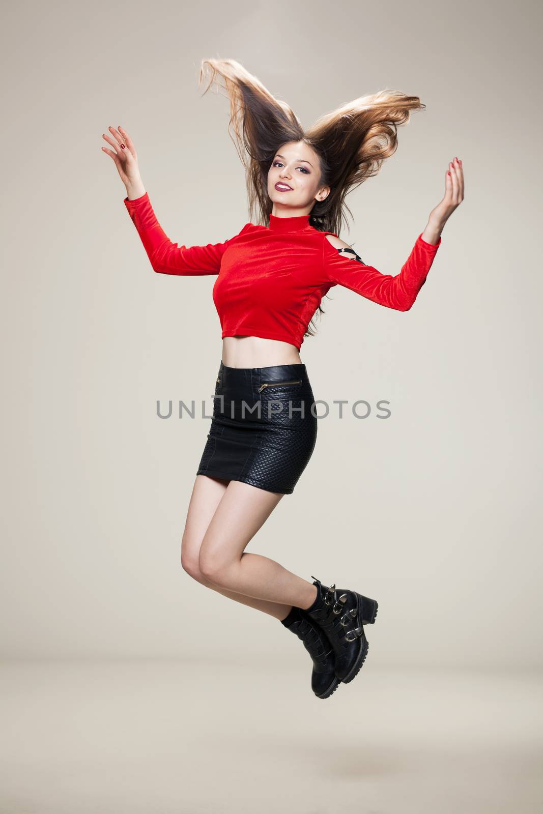 jumping girl in red shirt, short black dress and boots