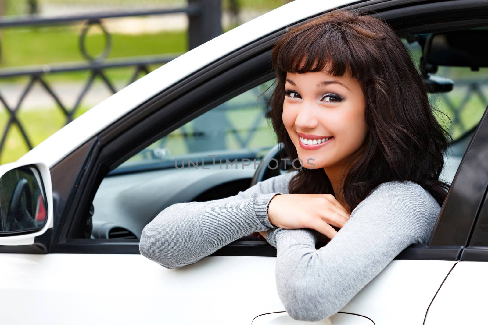 Pretty woman driver smiling to you from the white car by Nobilior