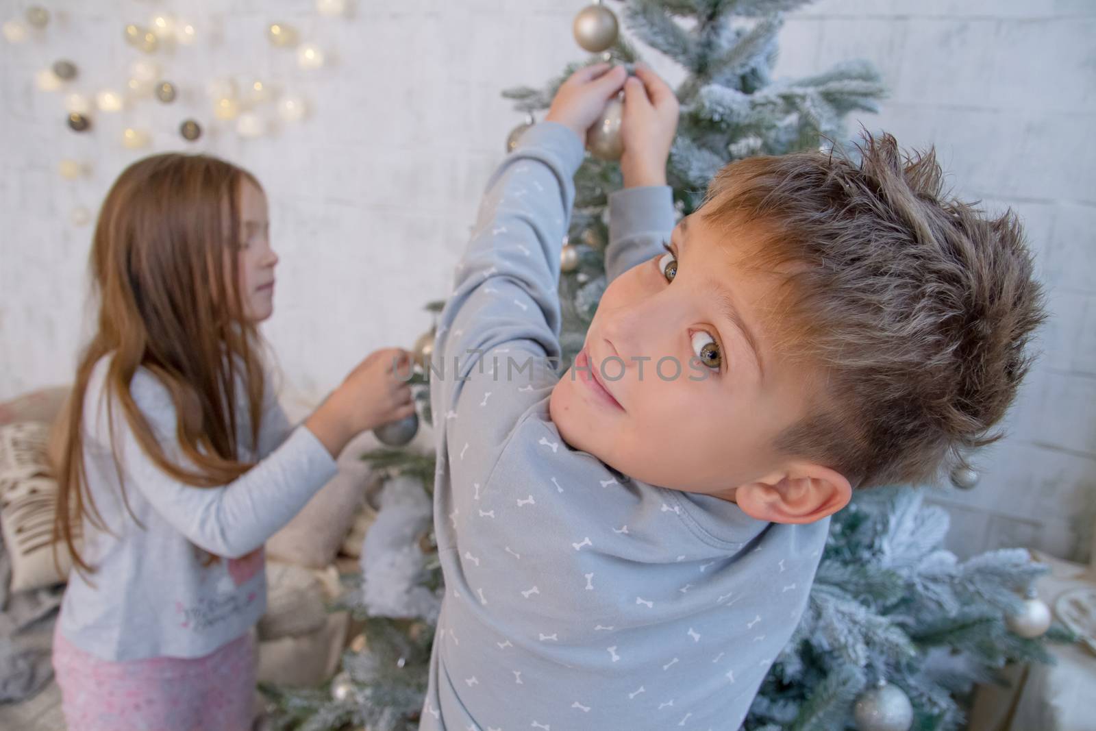 Boy and girl decorating Christmas tree with balls