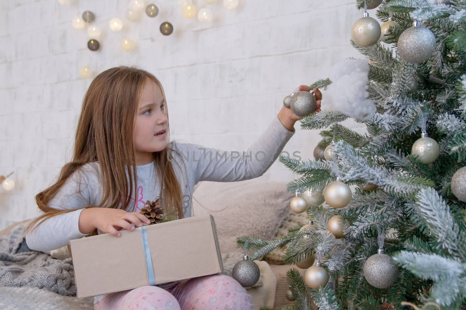 Girl under Christmas tree with ball and gift