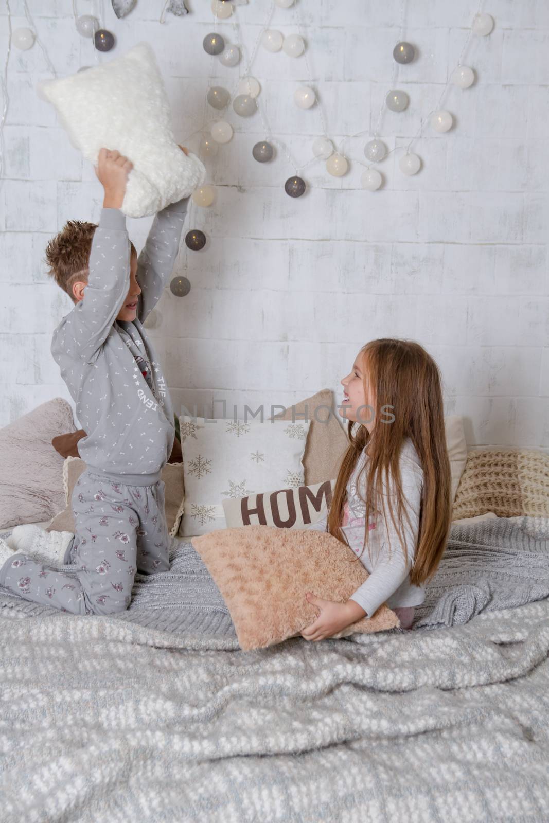 Siblings having pillow fight together on bed at Christmas