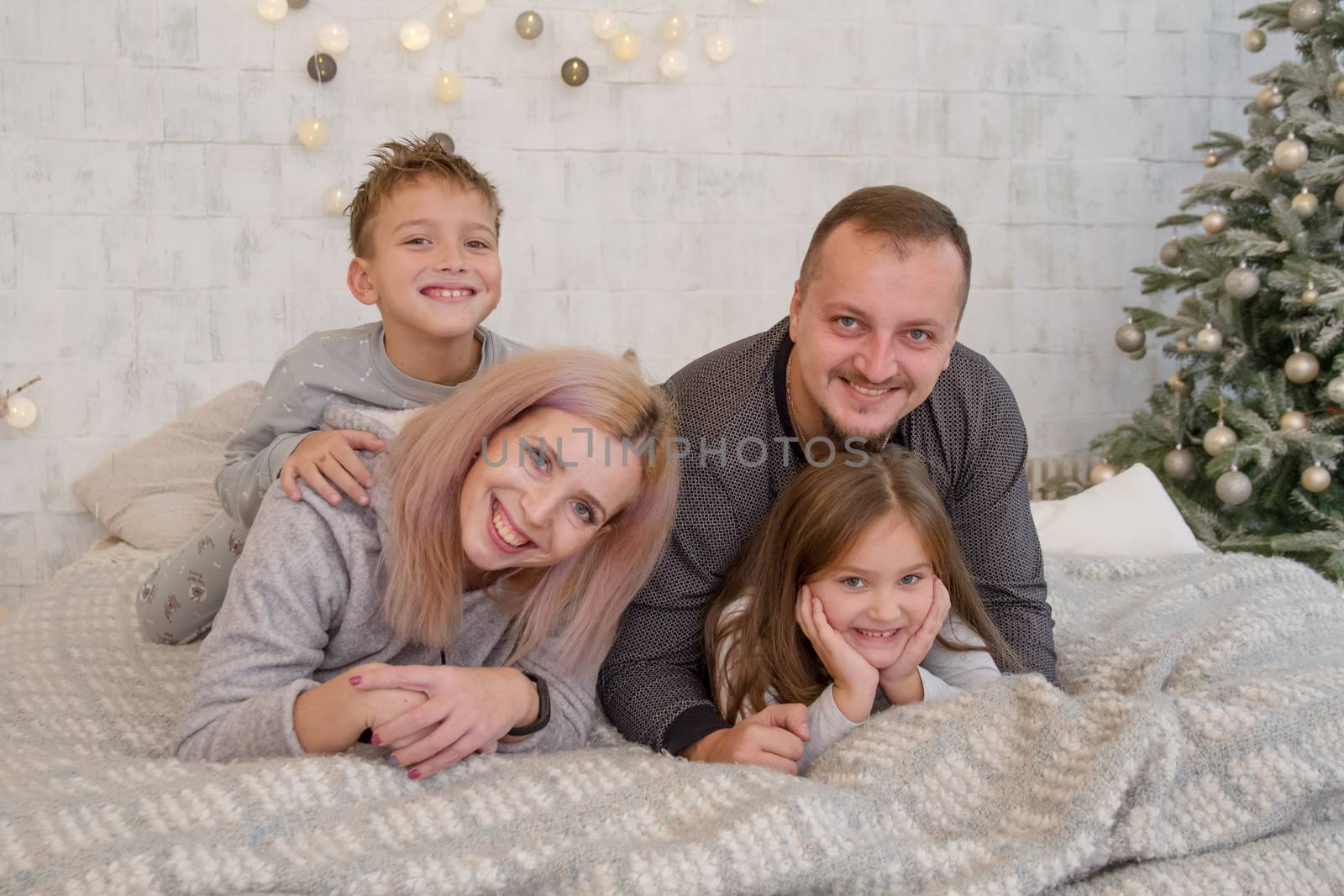 Happy family with two children under Christmas tree lying by Angel_a