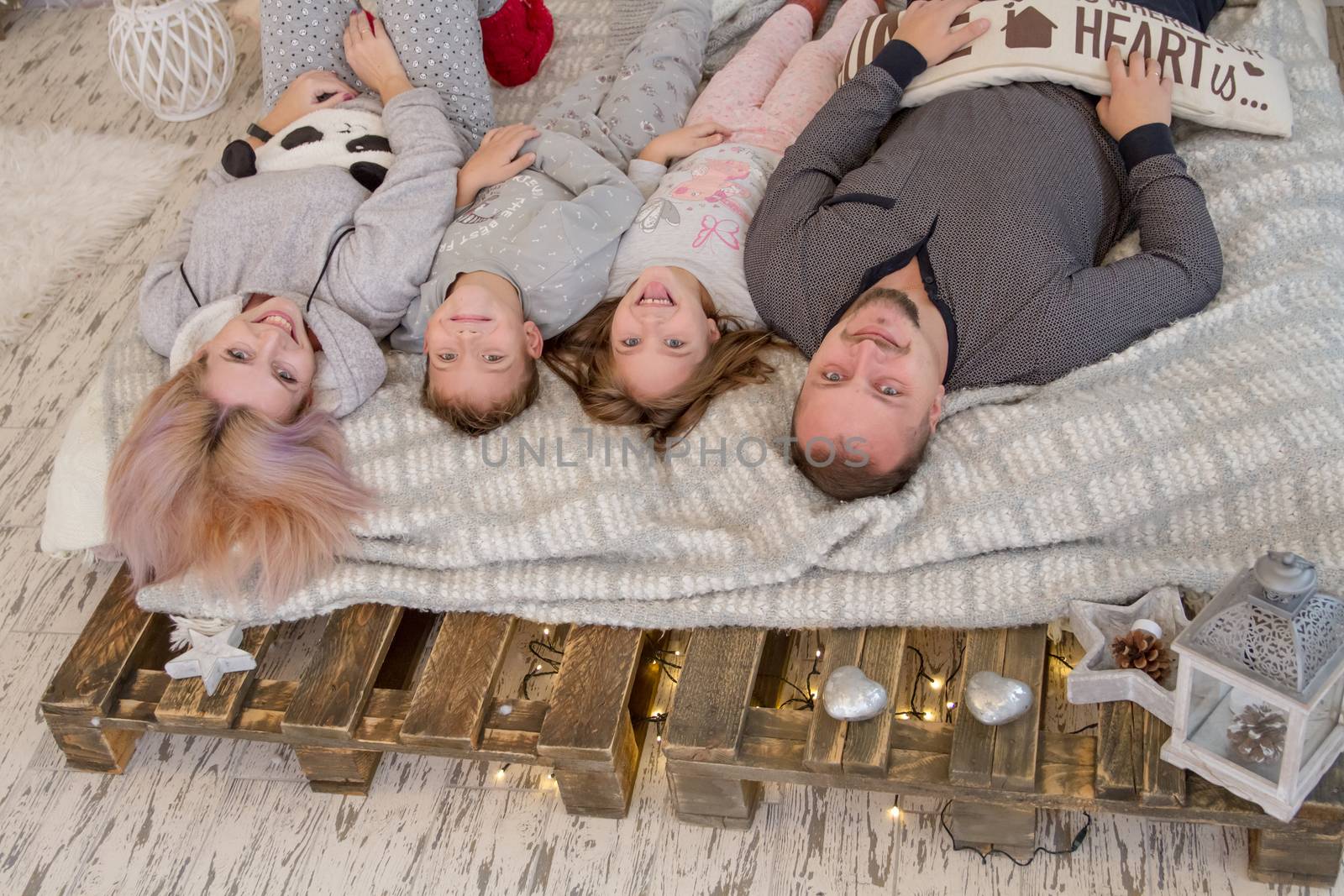 Happy family with two children lying on bed faces up