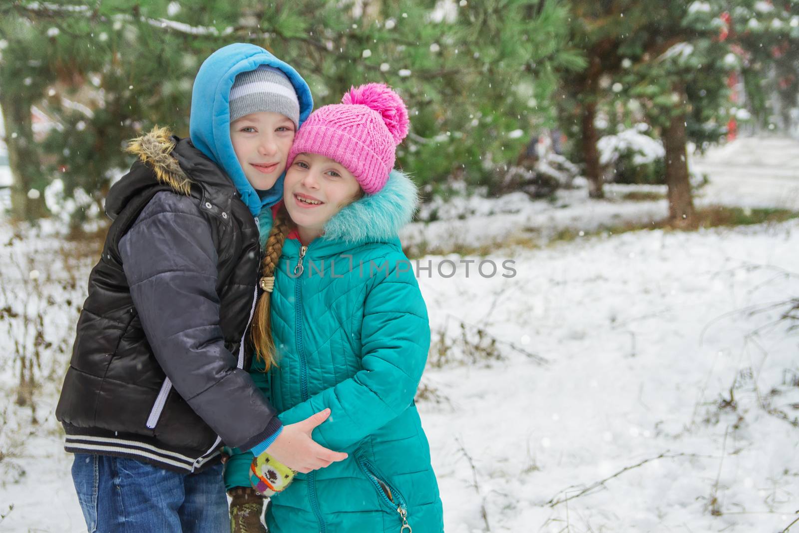 Sister and brother among snowy forest hugging