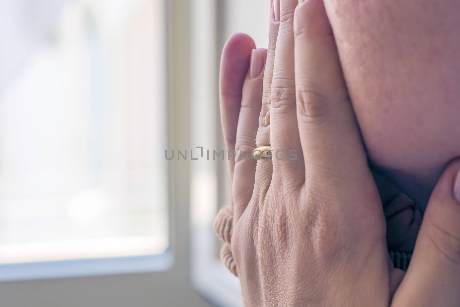 young woman covering her face with the hand looking at the window. close up shot.