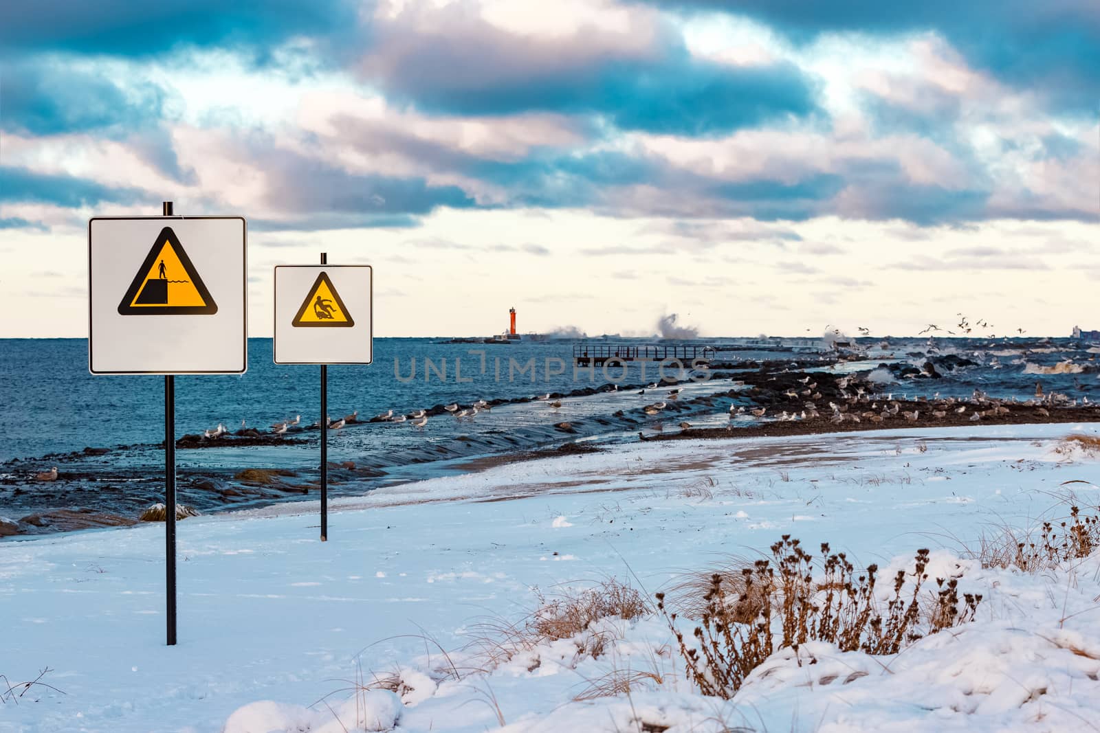 Two yellow warning signs on the winter beach