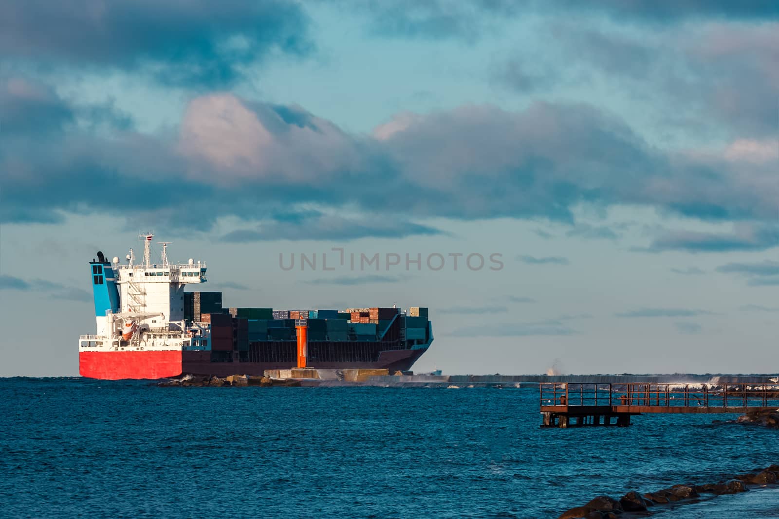 Full red container ship moving in still water