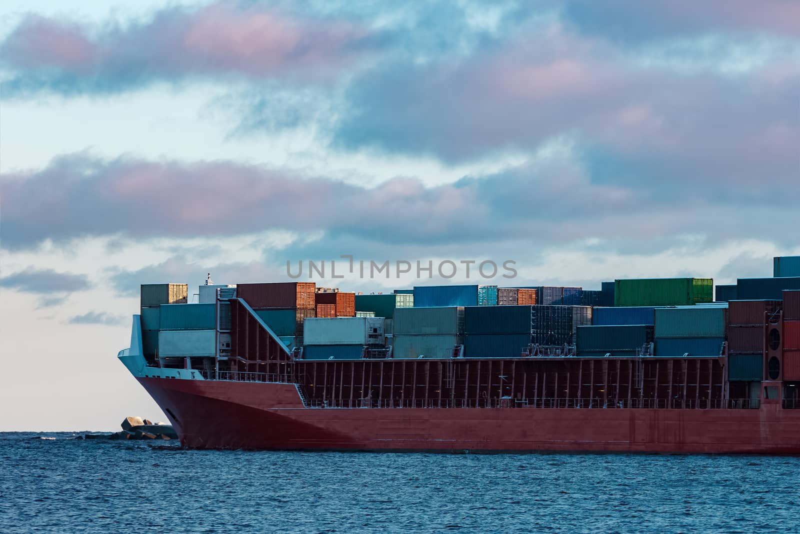 Full red container ship moving in still water